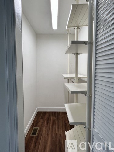A hallway with a white wall and a wooden floor.