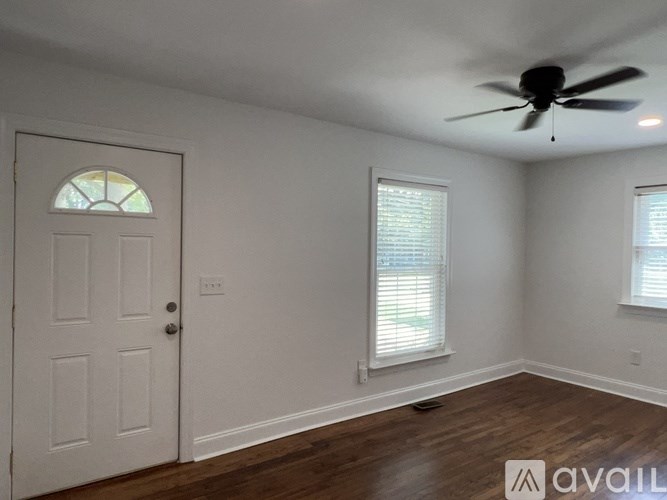 A room with a white door, two windows with blinds, and a ceiling fan.