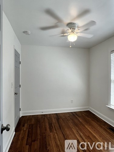 A room with a ceiling fan and wooden flooring.