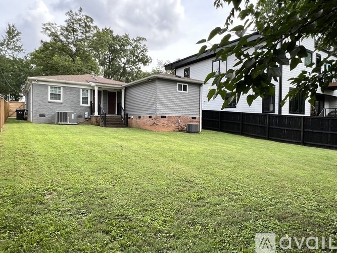 A backyard with a grey house and a green lawn.