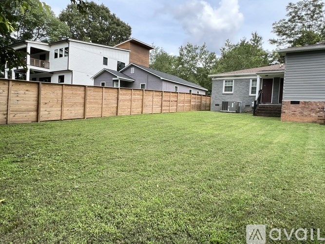 A backyard with a wooden fence and a house in the background.