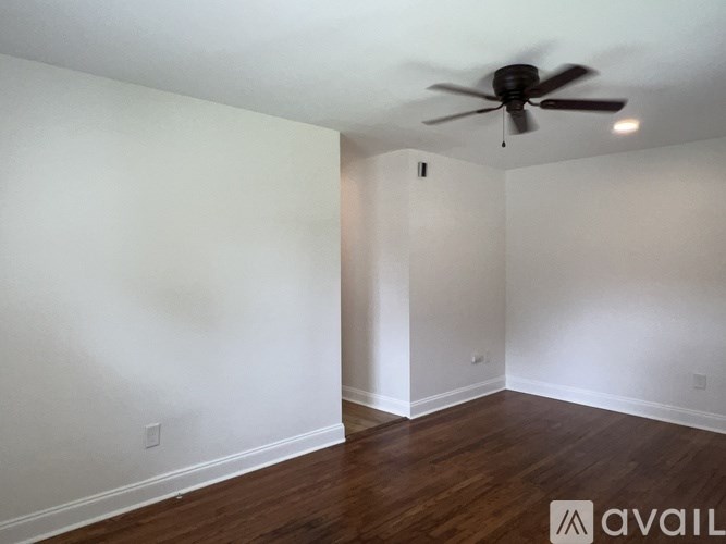 A room with a ceiling fan and wooden floors.