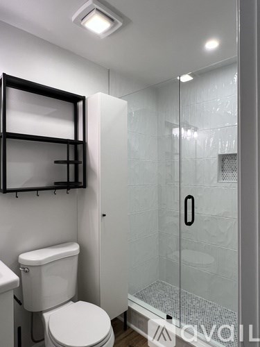 A white toilet with a glass shower stall in the background.