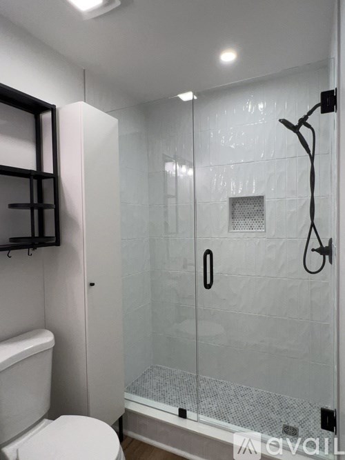 A bathroom with a toilet, a shower with a glass door, and a mirror above the toilet.
