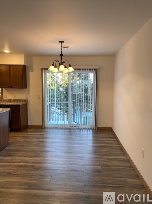 A spacious room with wooden floors and a chandelier.