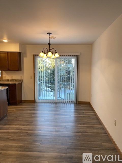 A spacious room with wooden floors and a chandelier.