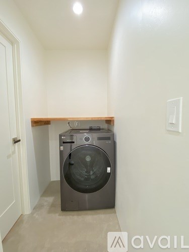 A washing machine is sitting in a small laundry room.