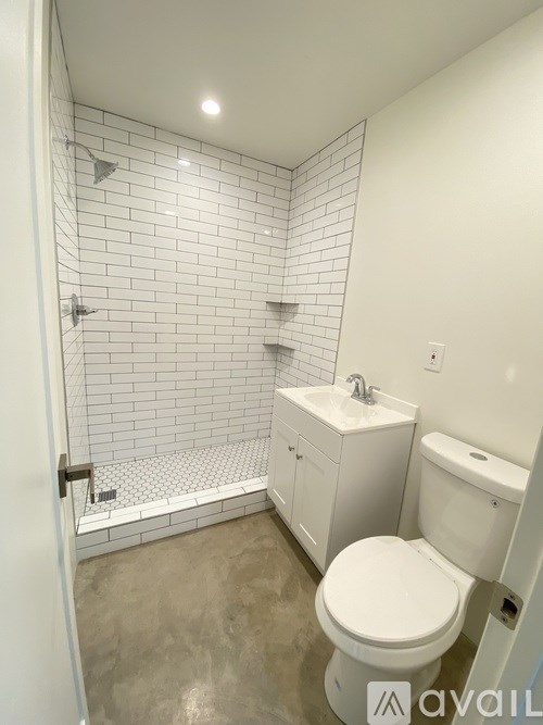A white toilet in a bathroom with a white tiled shower.