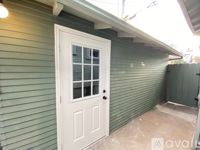 A white door with a window is on a green house.