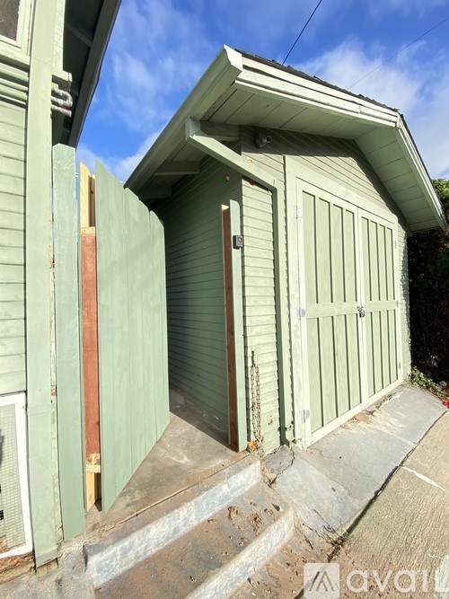 A green shed with a brown door and a small porch.