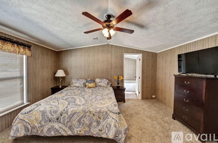 A bedroom with a bed, dresser, and ceiling fan.
