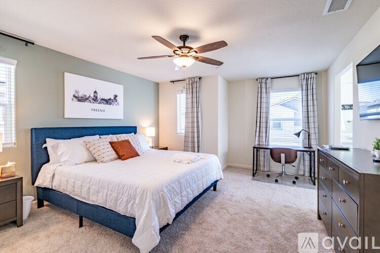 A bedroom with a large bed, a ceiling fan, and a chair.