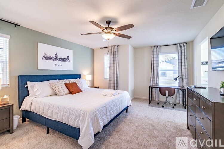 A bedroom with a large bed, a ceiling fan, and a chair.