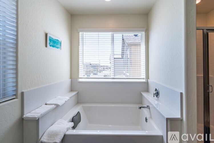 A white bathroom with a tub and a window.