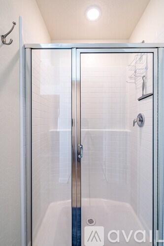 A shower stall with a glass door and a silver handle.