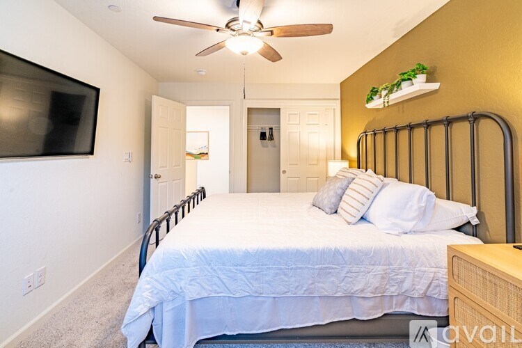 A bedroom with a bed, a ceiling fan, and a television.