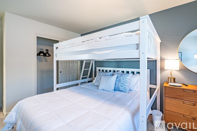 A white bed with a white comforter and blue pillows.