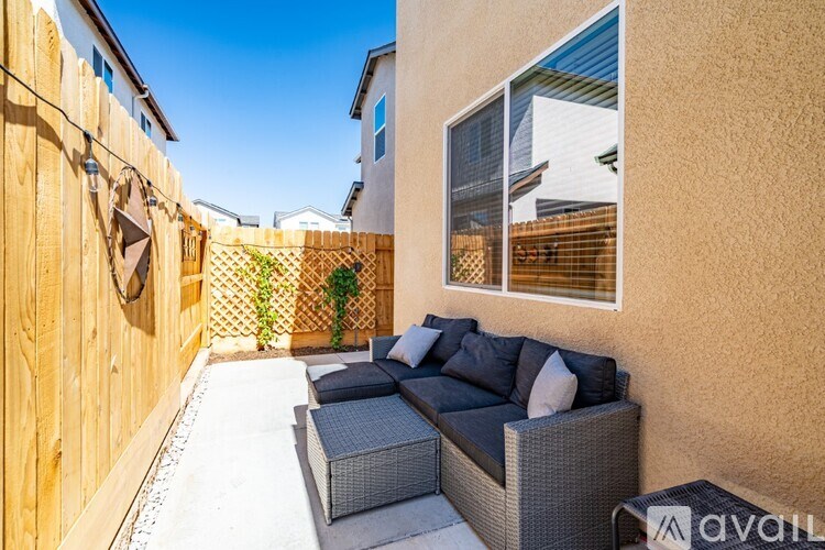 A patio with a grey sofa and a wooden fence.