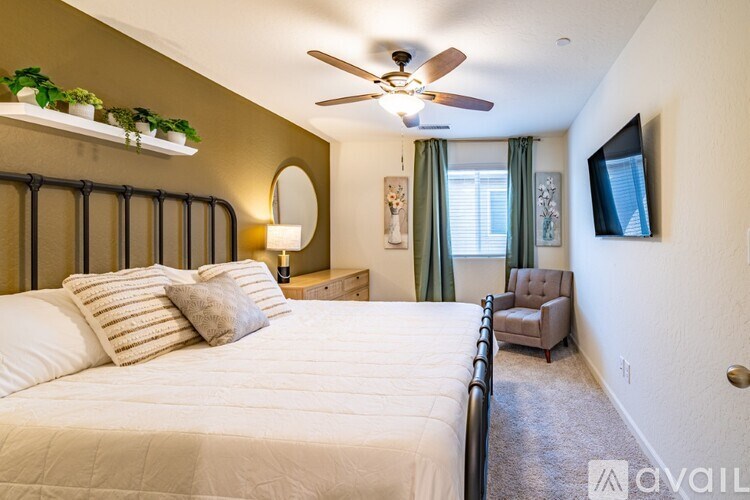 A bedroom with a large bed, a ceiling fan, and a chair.