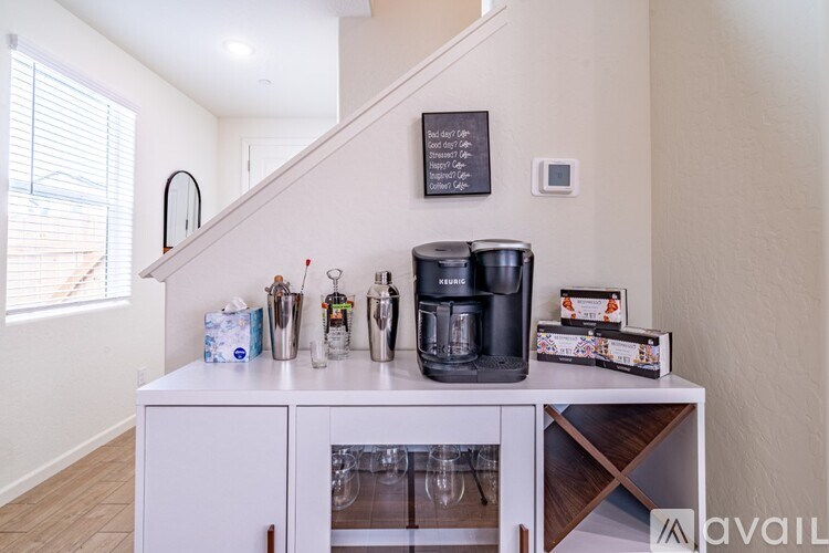 A kitchen area with a white cabinet and a coffee maker on top.