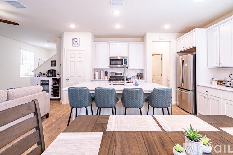 A modern kitchen with white cabinets and a wooden dining table.