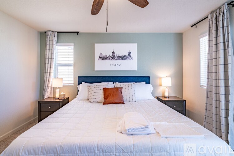 A bedroom with a bed, two lamps, and a ceiling fan.