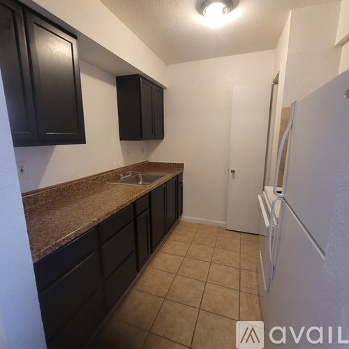 A kitchen with black cabinets and a white fridge.