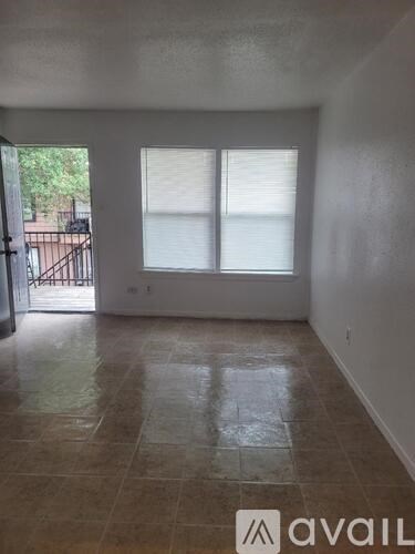 A room with tiled flooring and a sliding glass door leading to a balcony.