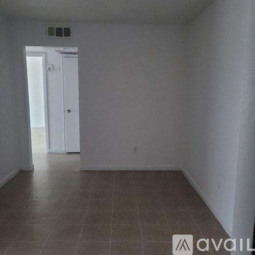 A room with a tiled floor and a door leading to another room.