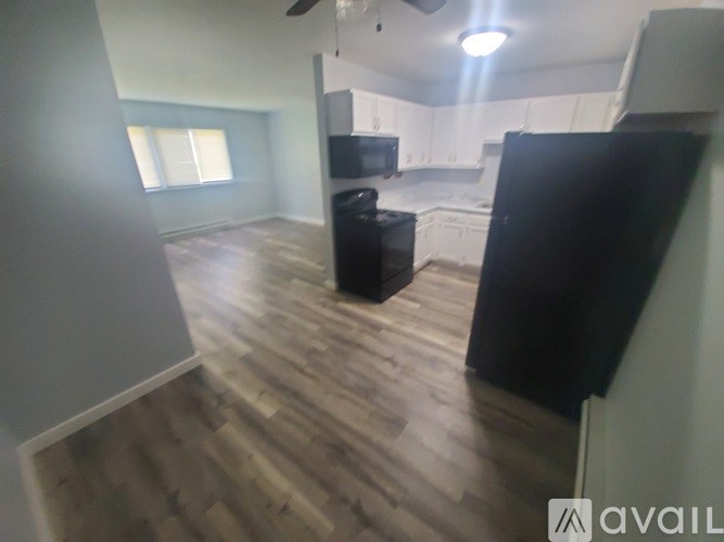 A kitchen with a black refrigerator and wooden floors.