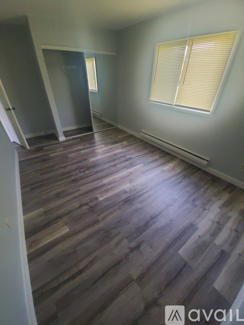 A room with wooden flooring and a window with blinds.