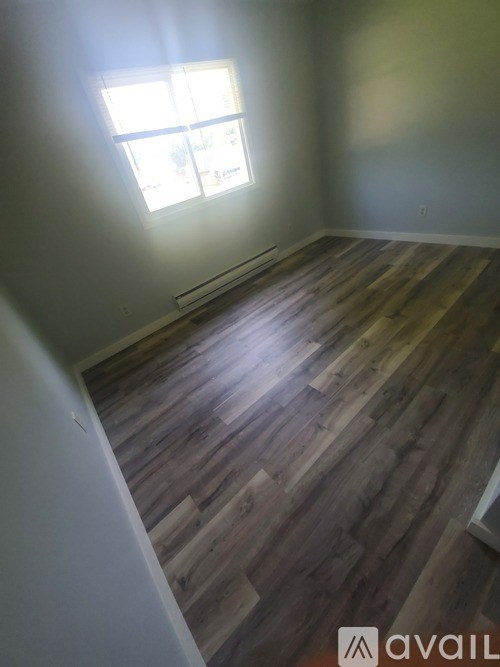 A room with wooden flooring and a window.