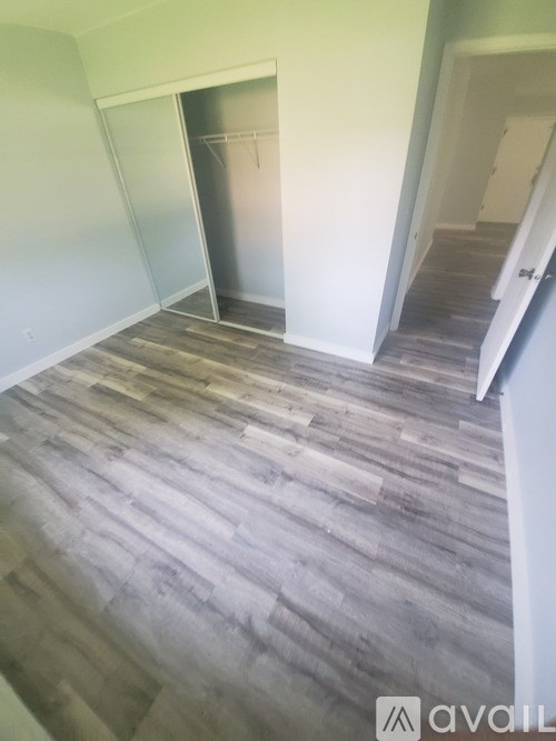 A room with a grey floor and a white wall with a doorway leading to another room.