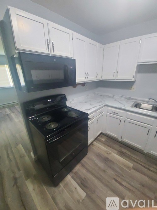 A kitchen with black appliances and white cabinets.