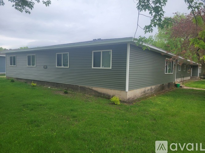 A grey mobile home with a green lawn in front.