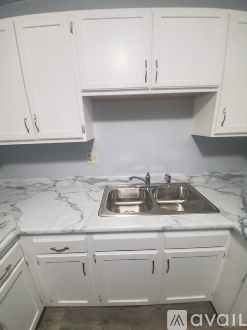 A kitchen with a marble countertop and white cabinets.