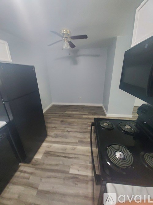 A kitchen with a black fridge, black stove, and a ceiling fan.