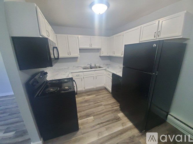 A kitchen with black appliances and white cabinets.