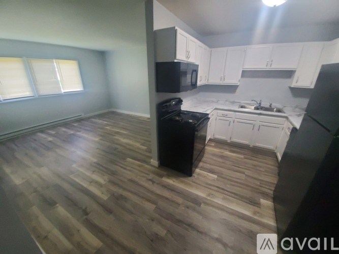 A kitchen with wooden floors and white cabinets.