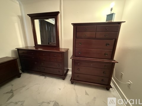 A large wooden chest of drawers sits next to a smaller one with a mirror on top.