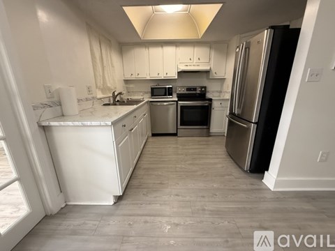 A kitchen with white cabinets and a refrigerator.