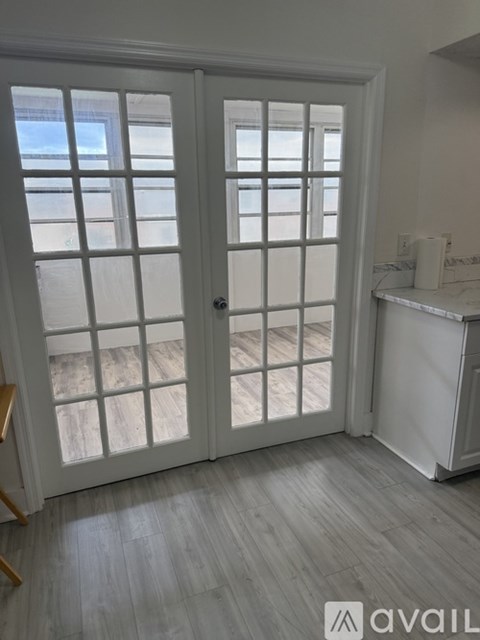 A white door with a window in the background and a white fridge to the right.