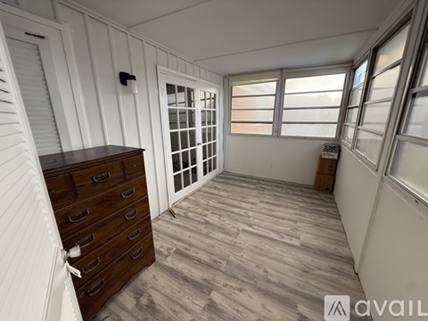 A room with a wooden floor and a white wall with a window.
