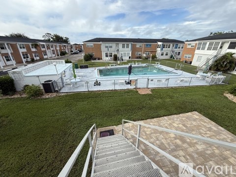 A view of a pool area from a balcony with apartment buildings in the background.