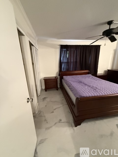 A bedroom with a bed, a ceiling fan, and a window with curtains.