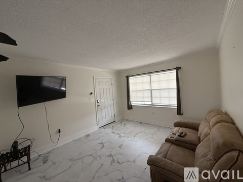 A living room with a couch, television, and window.