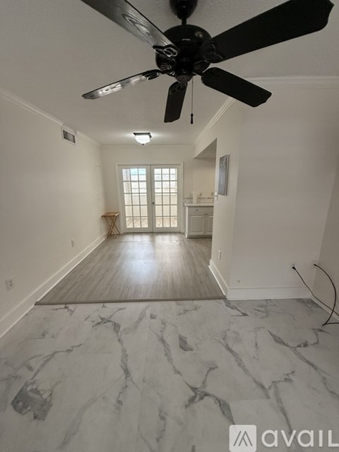 A spacious room with a ceiling fan and marble flooring.