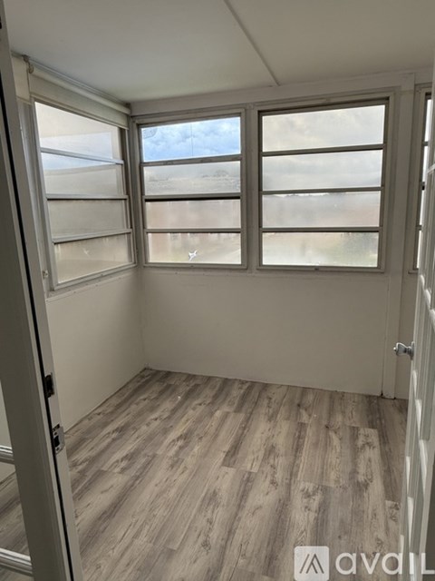 A room with a wooden floor and a window with blinds.