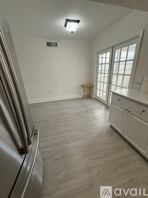 A kitchen with a refrigerator on the left and a window with a table in front of it.