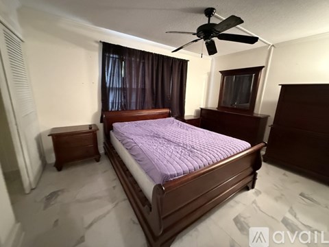A bedroom with a bed, a ceiling fan, and a window with curtains.